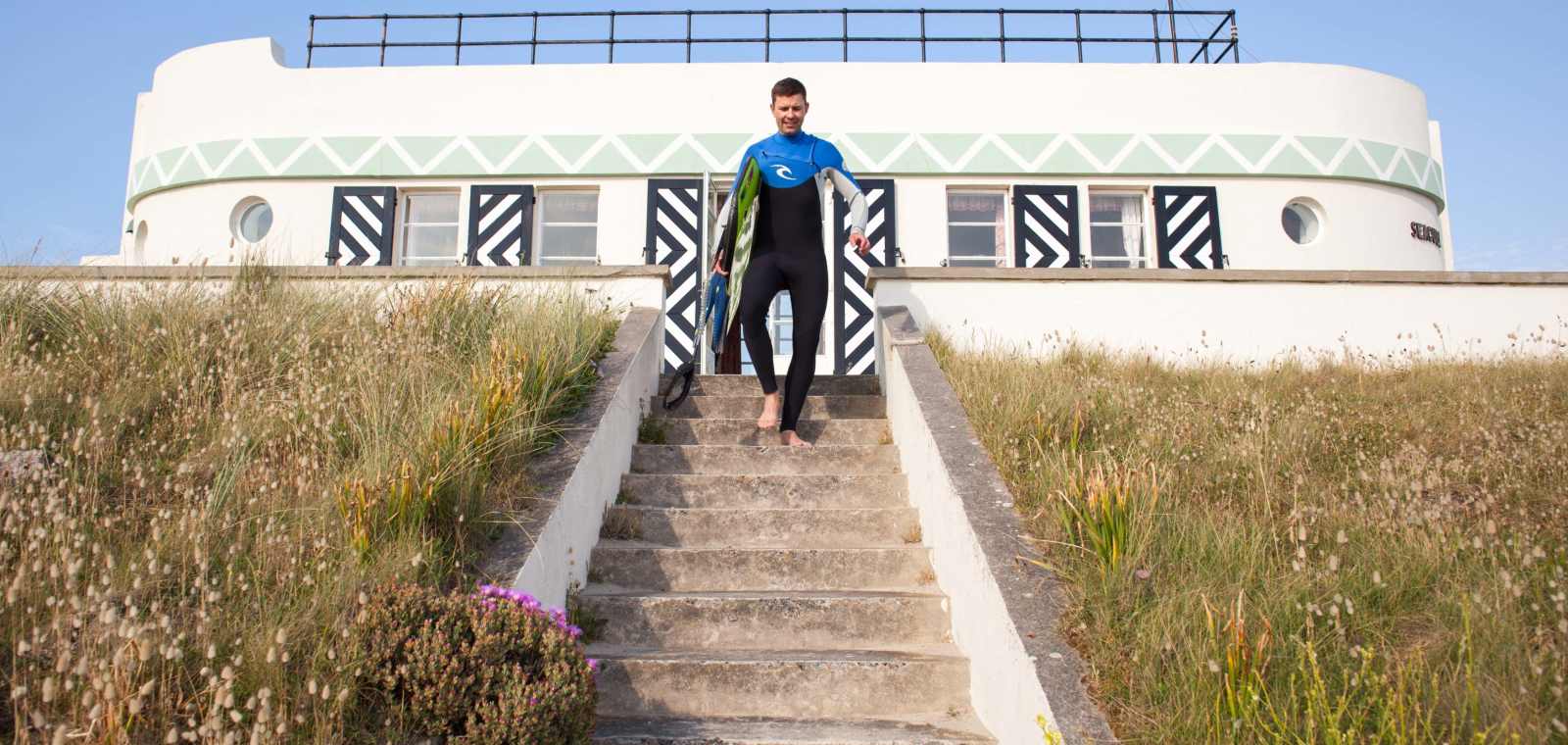 Surfer makes way down private steps to beach from Barge Aground