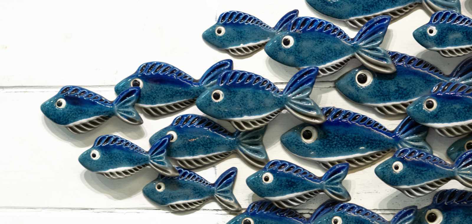 Blue ceramic fish swimming over white painted driftwood