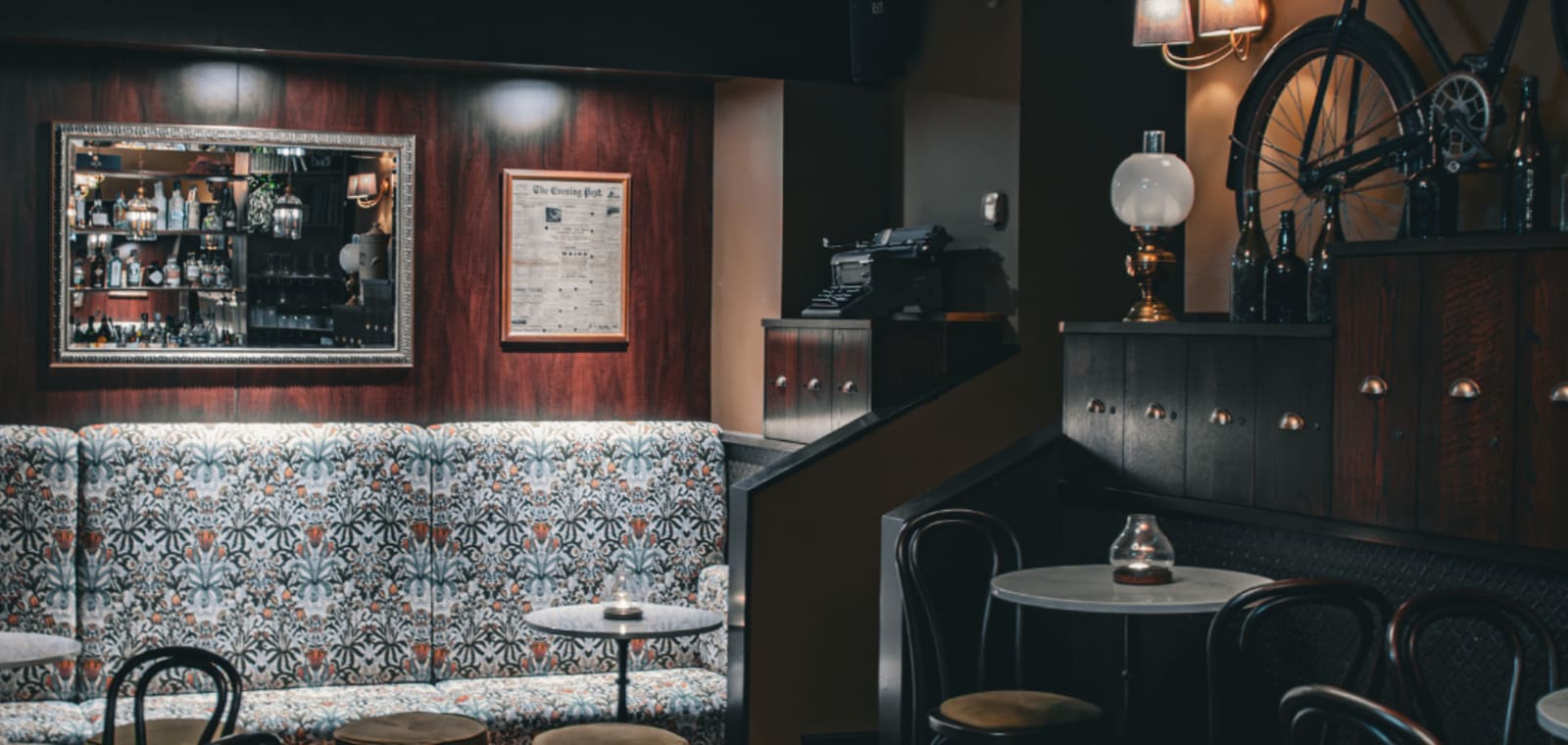 Curfew's interior featuring William Morris upholstered banquette, bent wood furniture, filing cabinets and a vintage bike on the wall.