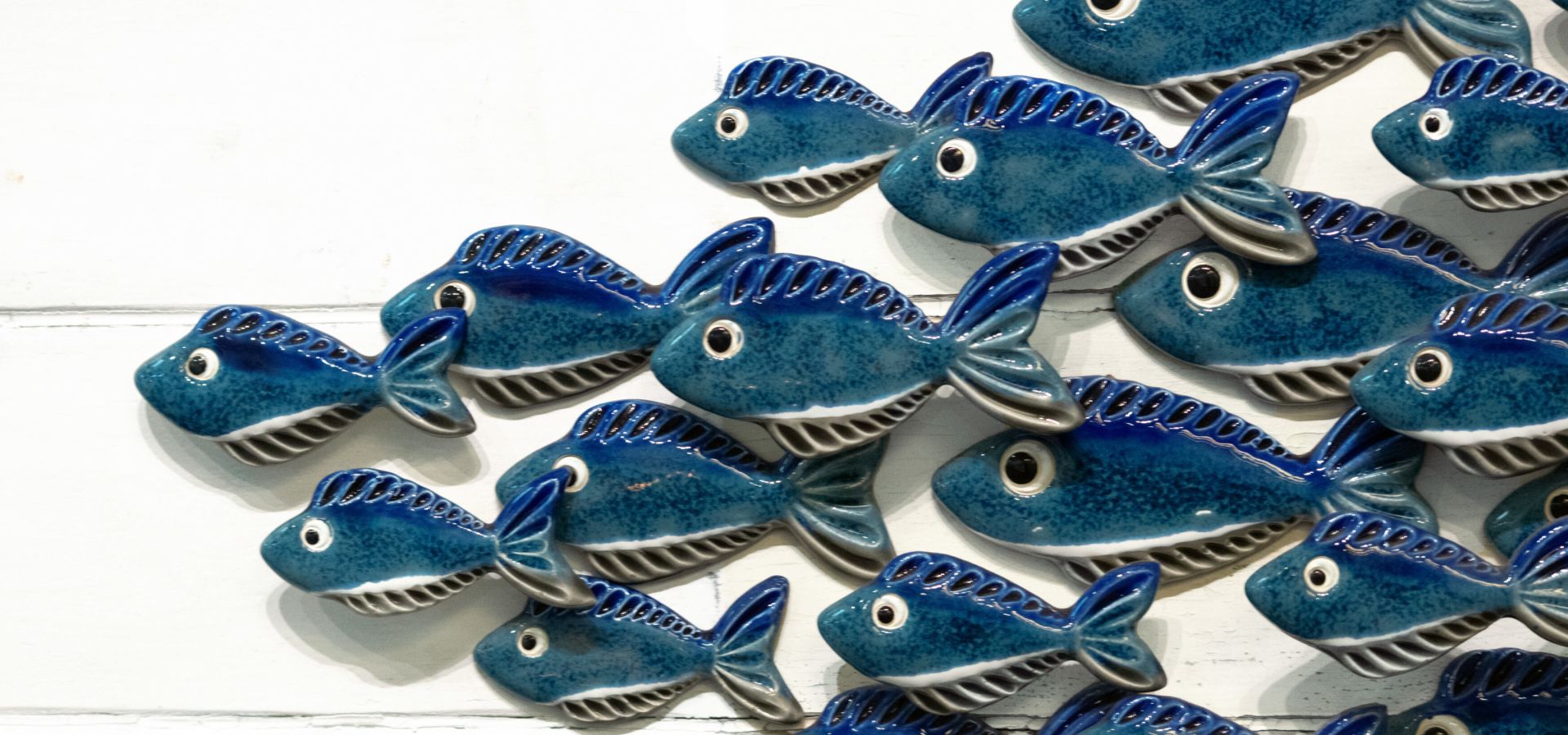 Blue ceramic fish swimming over white painted driftwood