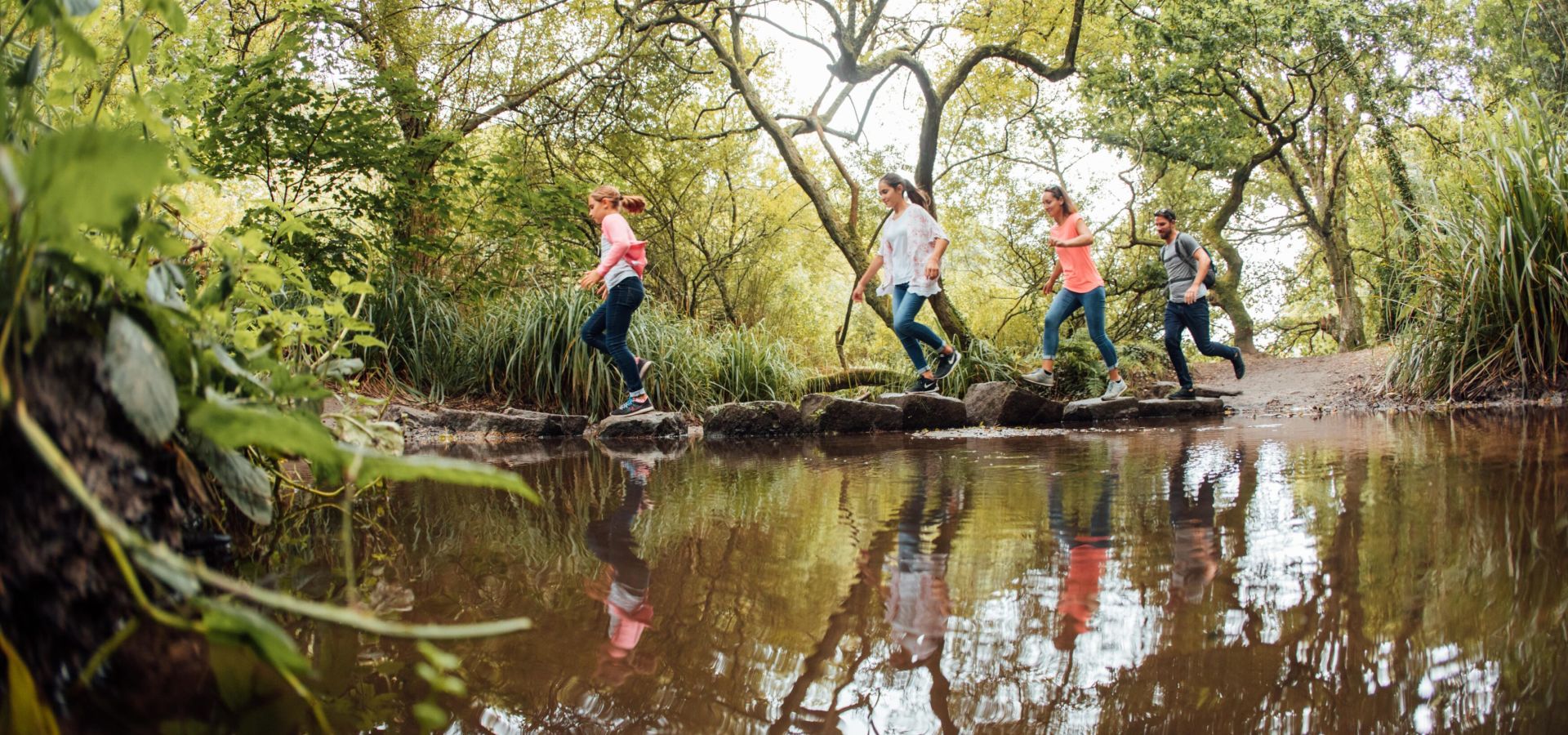 Family hoping over stepping stones in a stream at St. Catherine