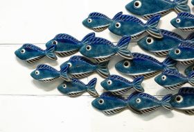 Blue ceramic fish swimming over white painted driftwood