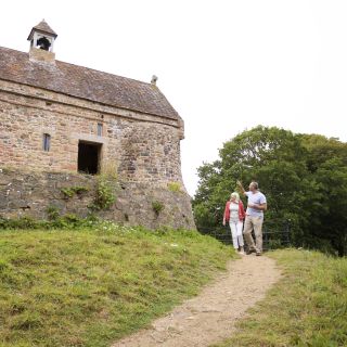 Couple walk on path from the chapel at La Hougue Bie