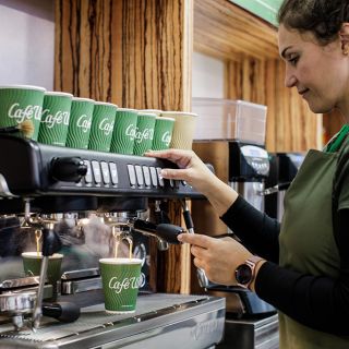 A barista prepares a cappuccino to go