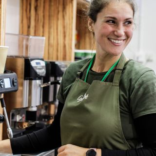 A smiling server pours a coffee