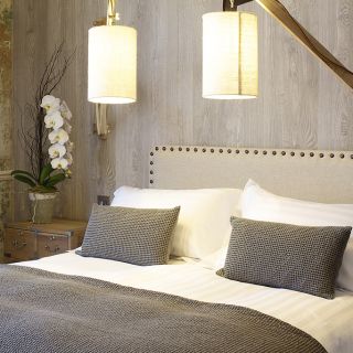 A king-size bed with decorative pillows and modern lamps