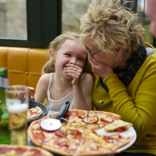 child and adult laughing whilst having pizza