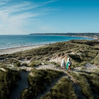 Surfers heading towards the water in St. Ouen