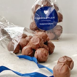 Handmade chocolate truffles pouring out of bag with Chocadyllic blue sticker and ribbon