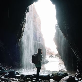 Person standing in front of the waterfall at Plu00e9mont Bay