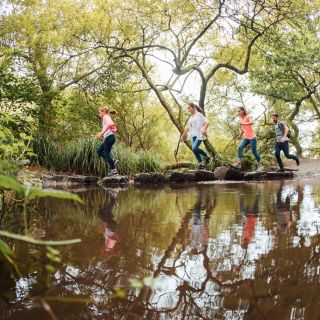 Family hoping over stepping stones in a stream at St. Catherine