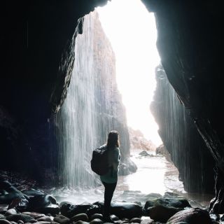 Person standing in front of the waterfall at Plu00e9mont Bay