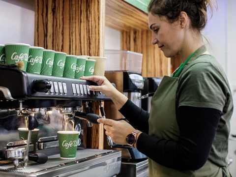 A barista prepares a takeaway coffee