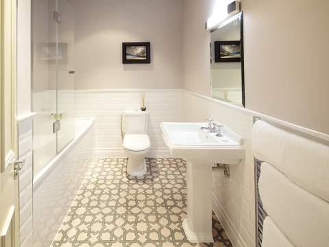 An ensuite bathroom with modern tiling, bath, shower, basin, and toilet