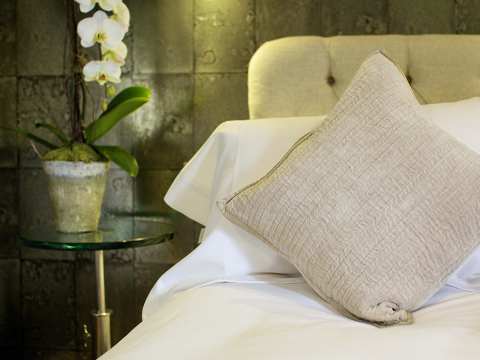 A king-size bed with green upholstered headboard, pillows, and an orchid