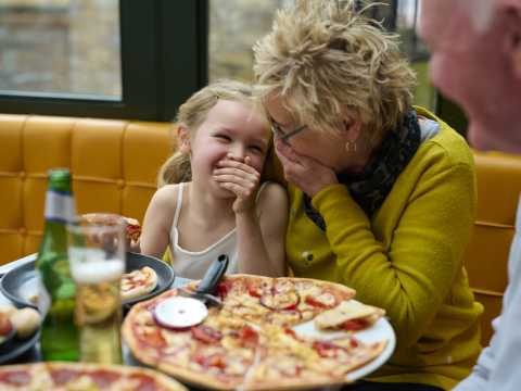 child and adult laughing whilst having pizza