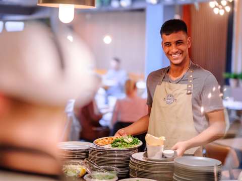 waiter getting ready to serve pizza, smiling