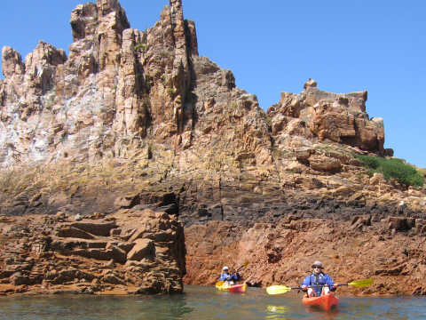 kayakers beneath cliffs