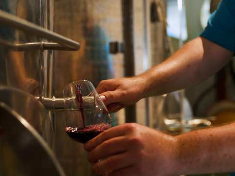Pouring a glass of red wine from the barrel at La Mare Wine Estate