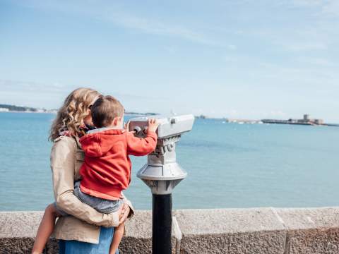 Mother and child look through binoculars at St. Aubin's Fort