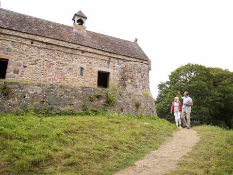 Couple walk on path from the chapel at La Hougue Bie