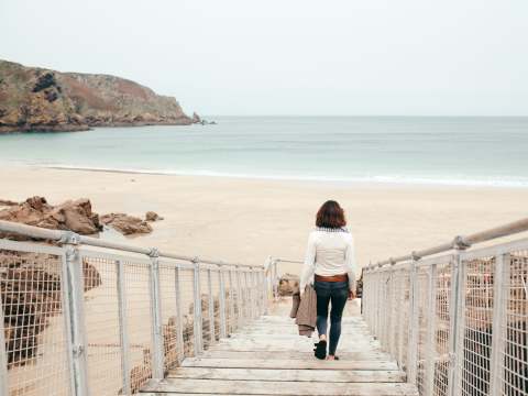 Person strolls down the walkway to Plu00e9mont Beach