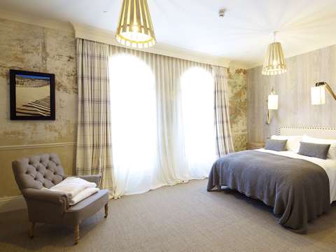 A large bedroom with modern wallpaper, curtains, and a king-size bed featuring decorative pillows