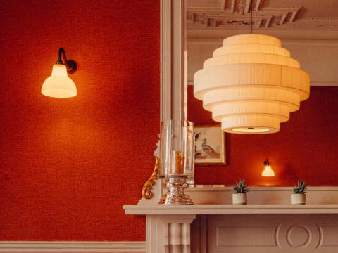 A dining chair upholstered in an attractive orange and cream striped fabric, beside a Victorian-style fireplace