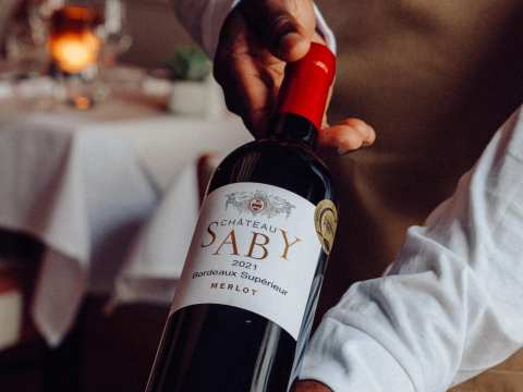 A waiter holds a bottle of Saby wine