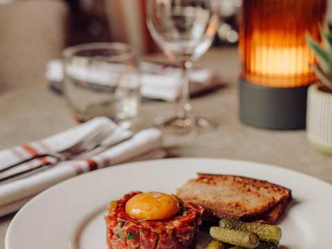 Beef tartare plated on a white brasserie-style plate, pictured on an elegant marble dining table