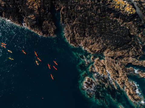 Kayakers exploring the north coast seen from a drone