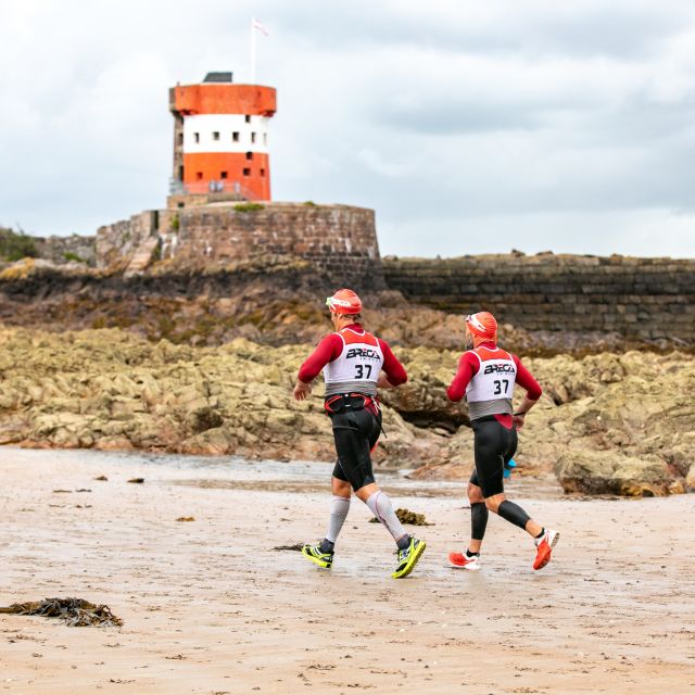 Runners on the beach in front of Archirondel Tower