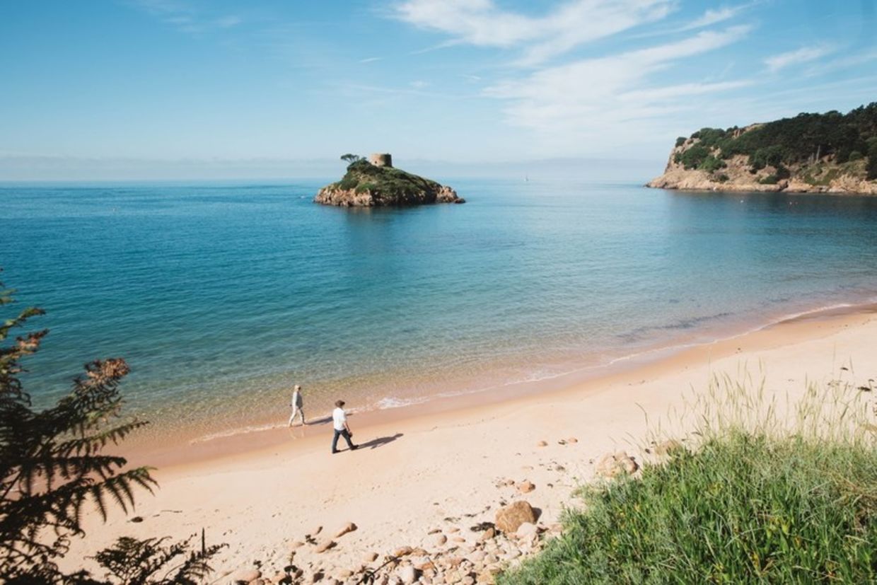 View over the beach at Portelet bay with couple walking along shoreline