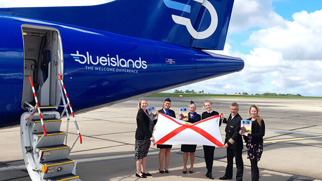 Staff stood in front of Blue Islands plane and stairway with Jersey flag