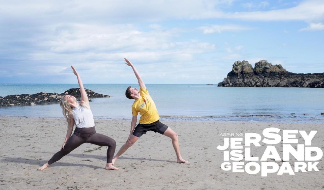 Two people on the beach in a yoga pose