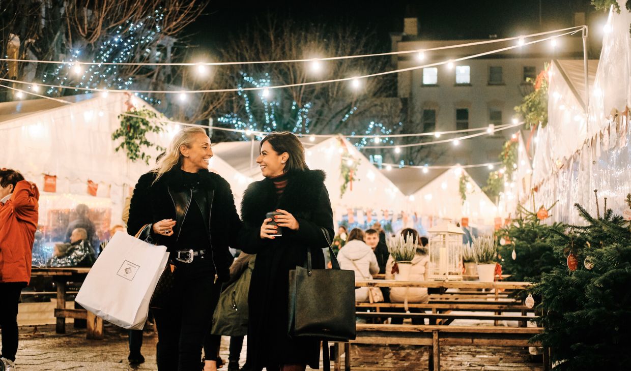 Two women walking and laughing at a Christmas market