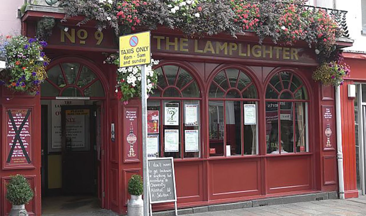 A picture of a traditional english pub with a red, wooden exterior and large windows.