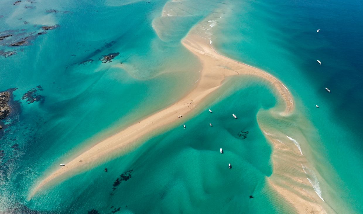 Aerial shot of the Minquiers sandbank off the coast of Jersey with golden sand and turqoise waters
