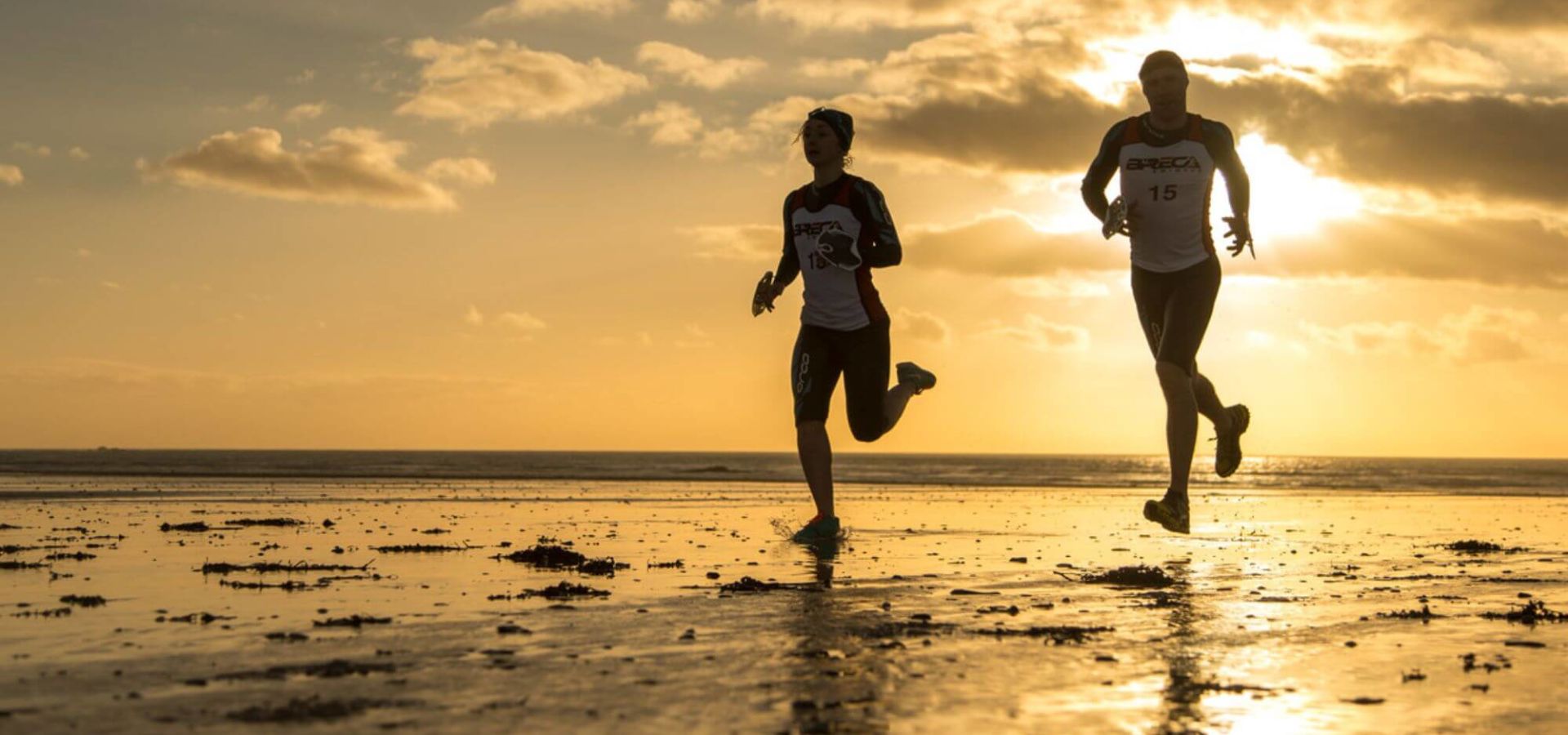 two people running on the beach at sunset