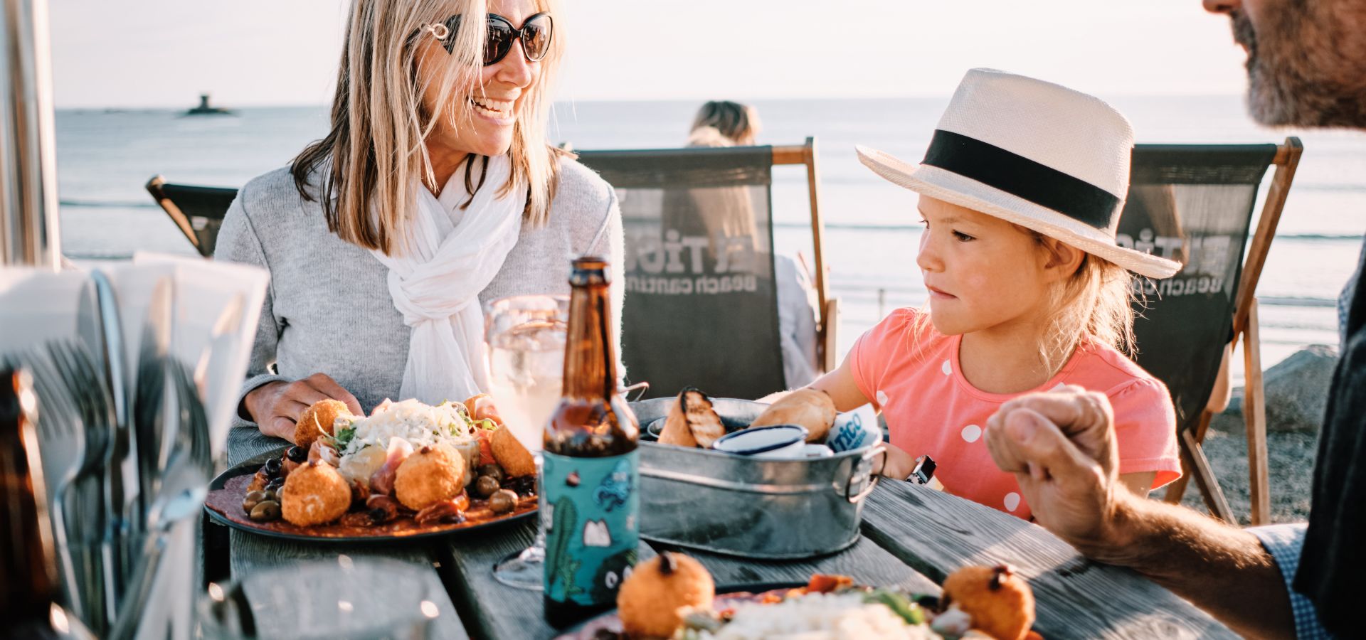 Couple with young child enjoying al fresco dining in the sun overlooking the sea