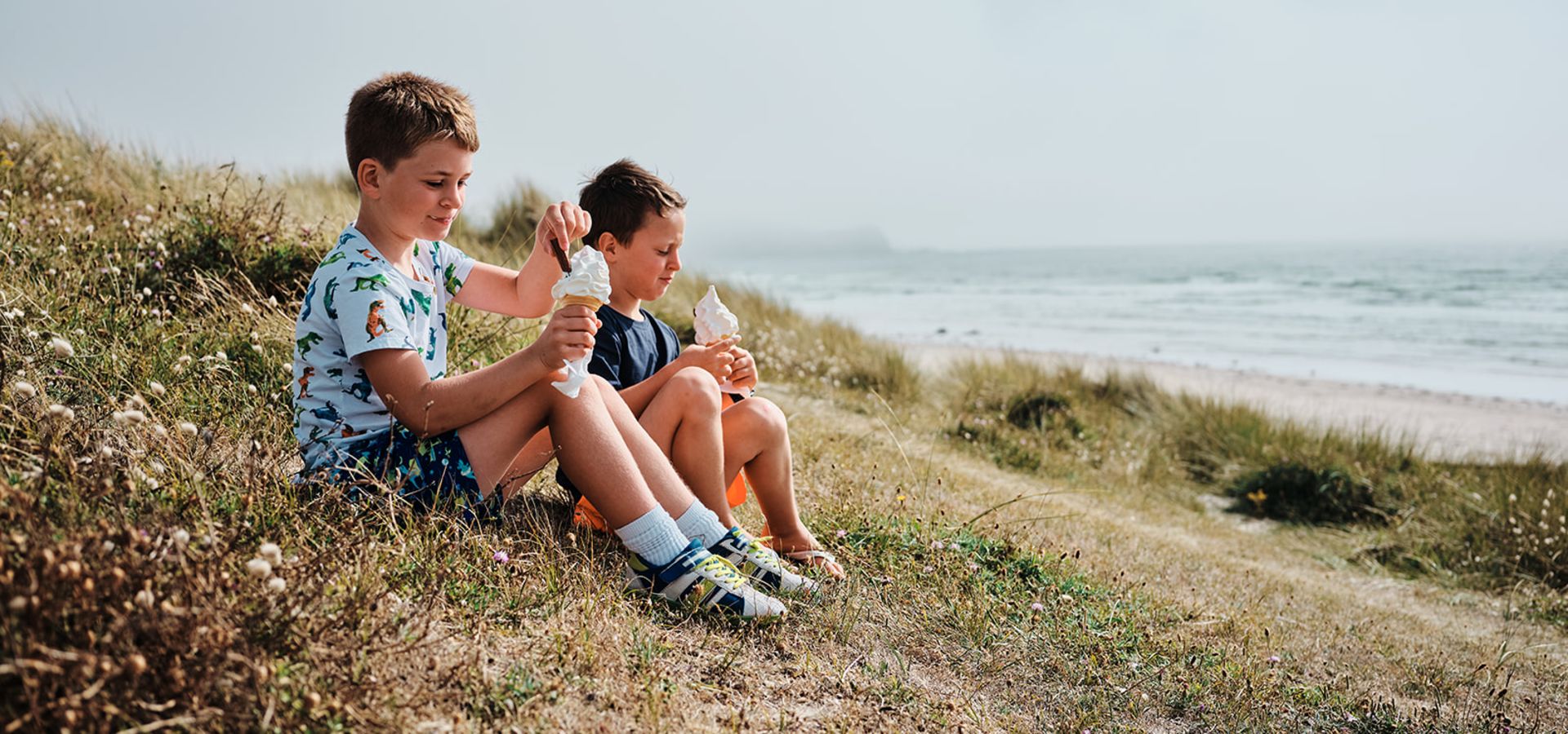 children eating ice cream sitting on the sand dunes