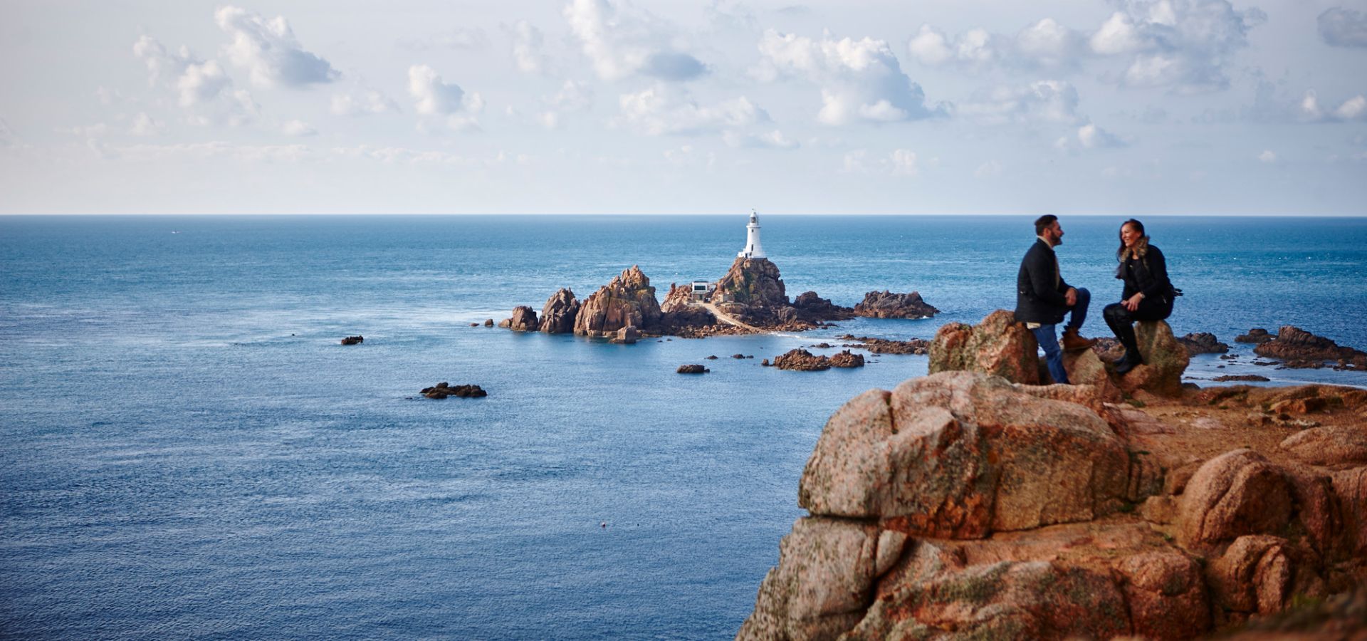 A couple sat in front of Corbiere Lighthouse
