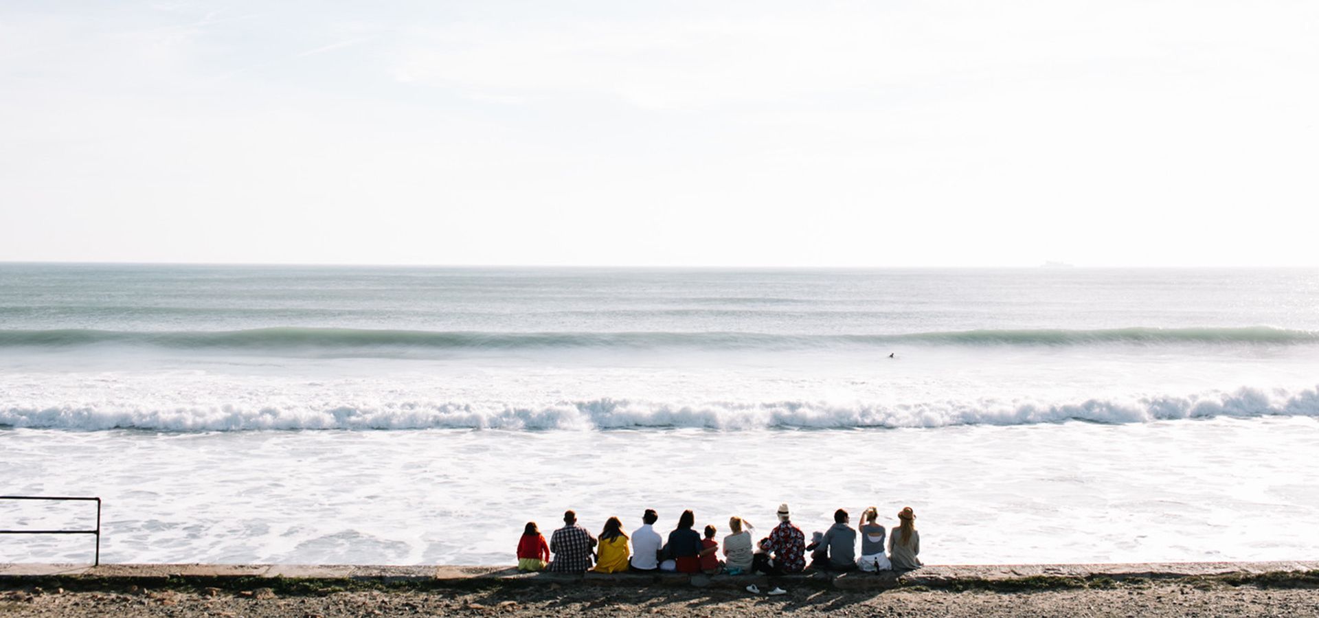 A group of people sitting on the sea wall at St. Ouen