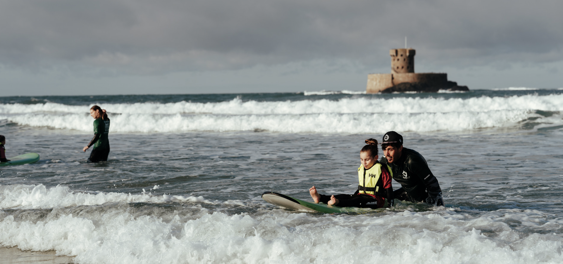 Girl with additional needs on a surfboard with the help of a carer