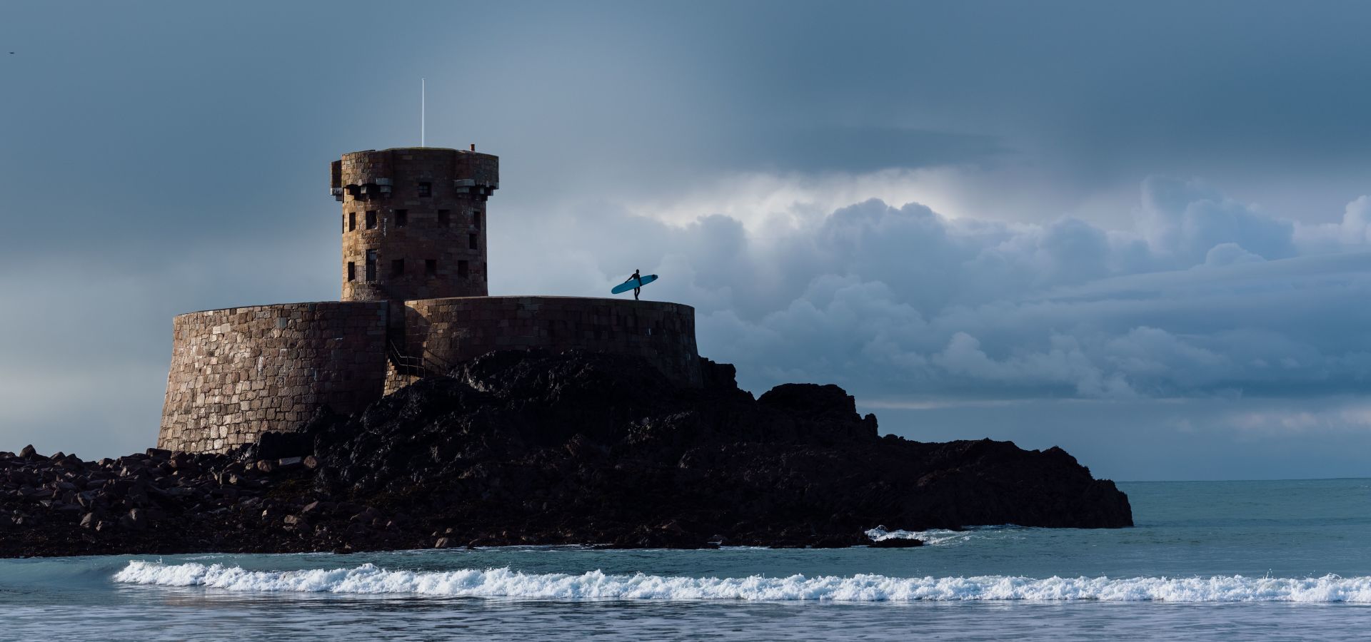 Surfer standing on a tower in the sea