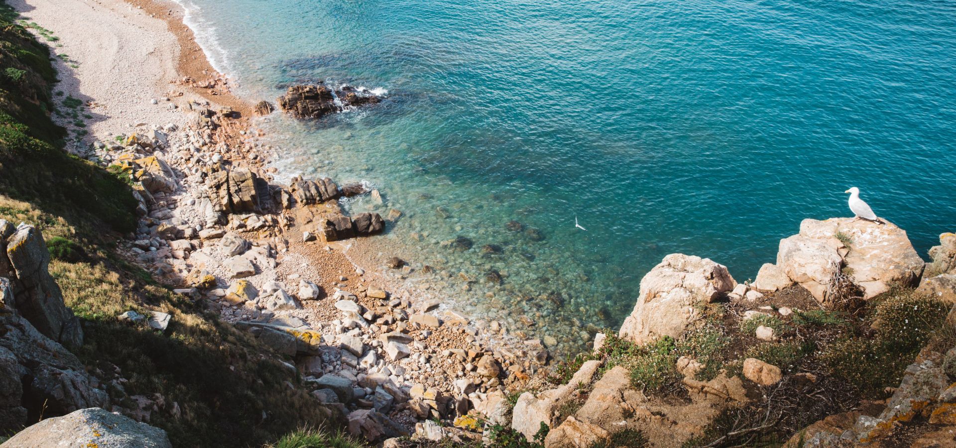 rocks surrounding pebble beach and turquoise sea