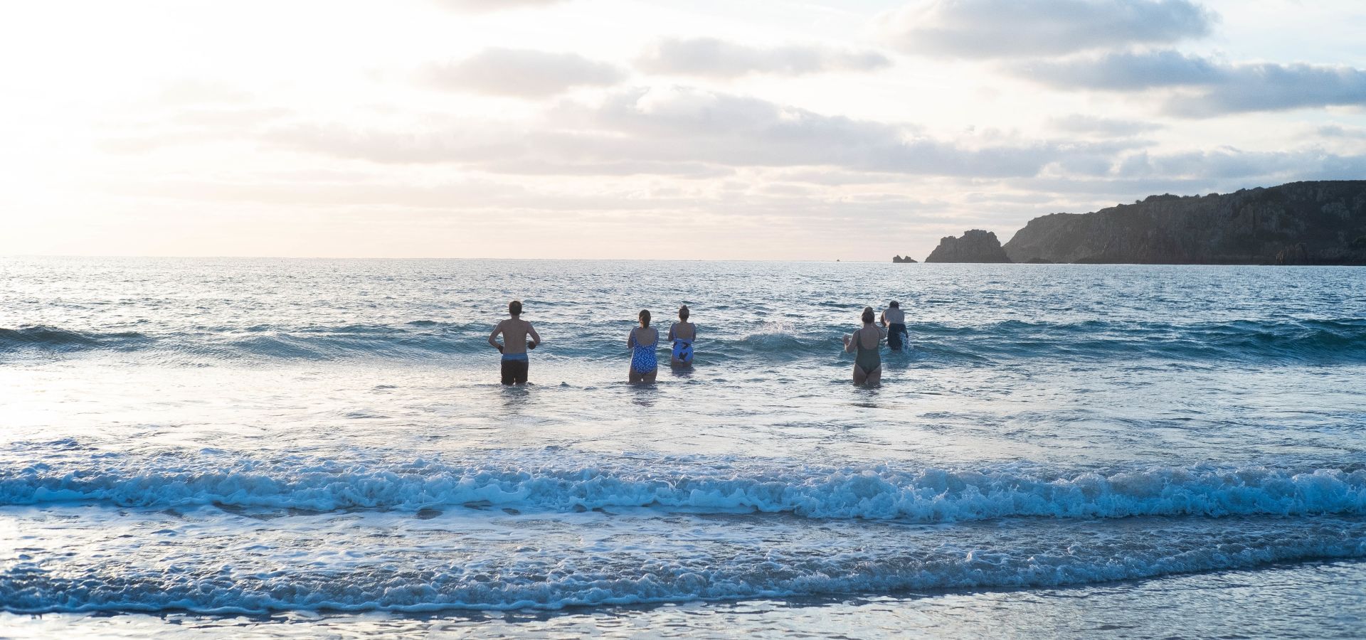 Group of people walking into the sea in winter