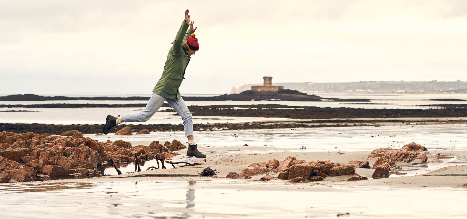 Sophie Hellyer jumping in a puddle on the beach in Jersey
