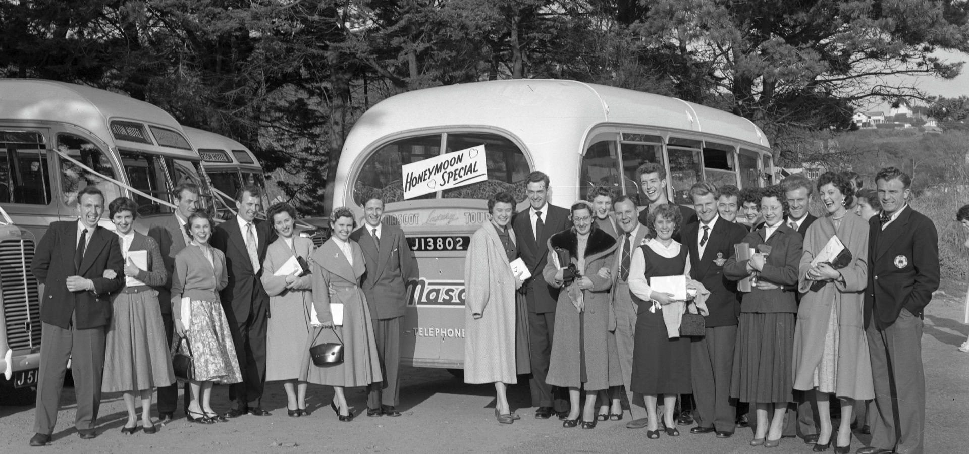 Group of couples standing in front of a vintage bus