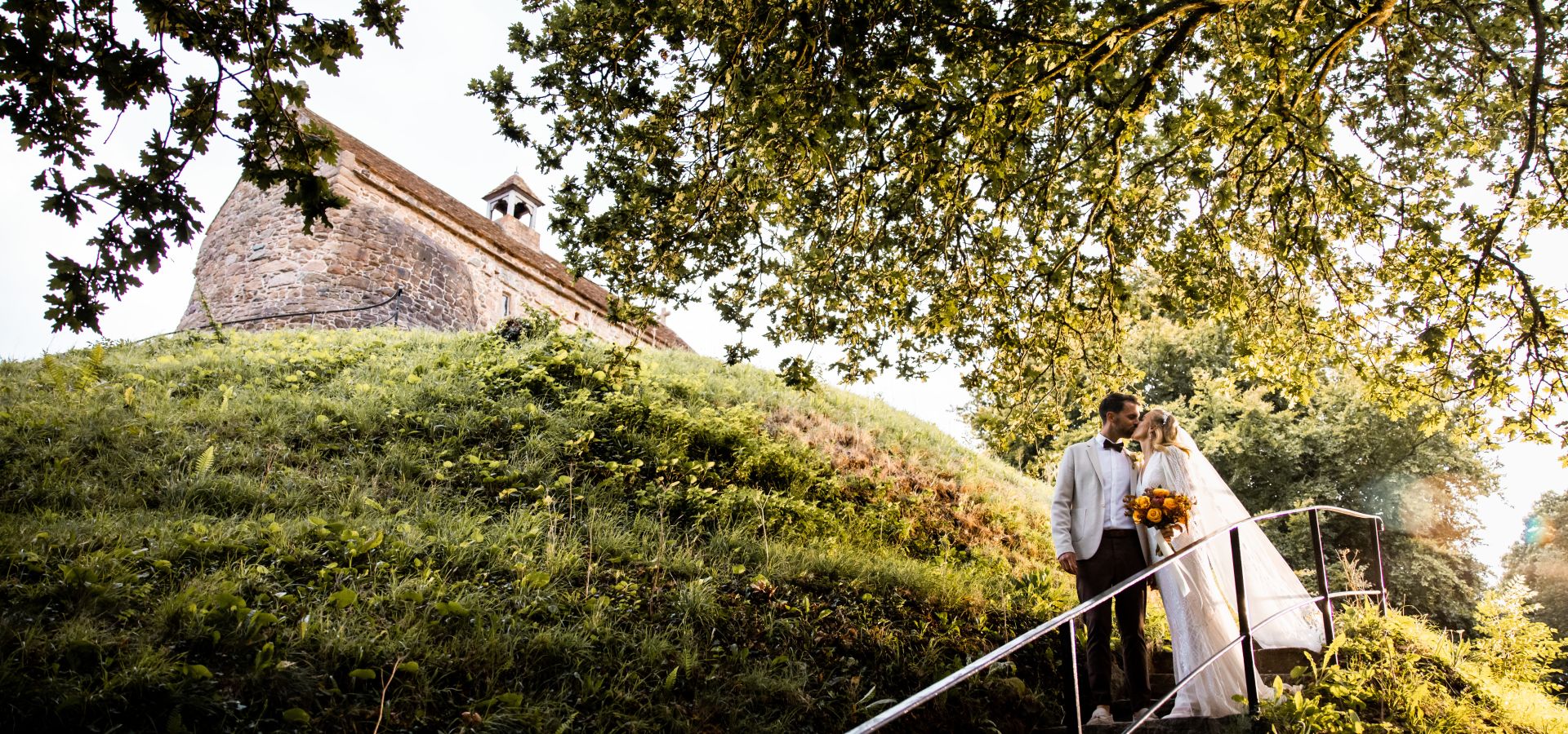 Just married couple underneath a tree and historic chapel